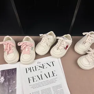 Detail of trendy children's white sneakers with glitter star accents and pink laces