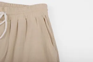 Close-up detail of men's beige corduroy pants with elastic waistband and drawstring