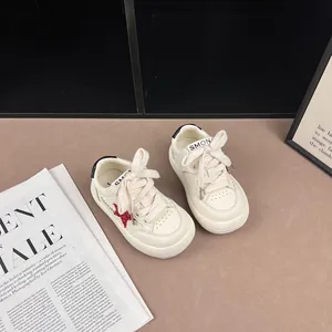 Close-up of white children's sneakers with red star embroidery and thick laces