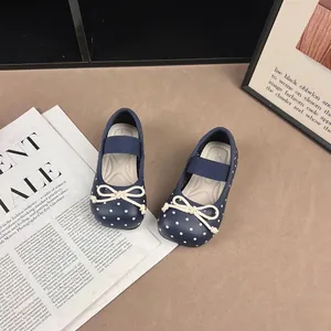Close-up of navy blue polka dot baby shoes with cute bow detail on magazine background