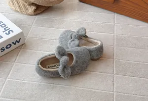 Close-up detail of grey fuzzy girls' winter shoes with a cute plush bow decoration