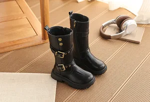 Klassische schwarze Mädchenstiefel mit Schnallen auf einem warmen Holzboden im Detail