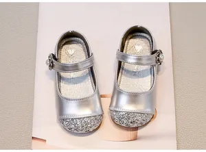 Primo piano della punta glitterata argento e della fibbia in perle per scarpe da bambina