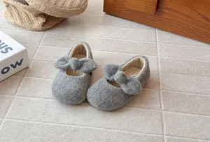 Close-up of grey fuzzy girls' Mary Jane shoes featuring a soft plush bow detail.