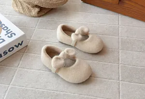 Macro view of beige fuzzy toddler girl shoes with plush bow detail