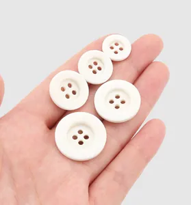 Macro view of high-end white resin 4-hole buttons in various sizes shown on a palm