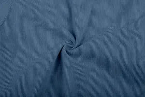 Macro detail showing the soft ribbed texture of blue corduroy fabric for men's pants.