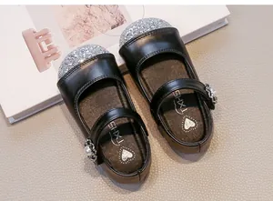 Dettaglio di scarpe Mary Jane nere da bambina con punta glitter argento e fibbia di perla