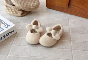 Close-up detail of plush beige toddler shoes featuring large decorative bow and soft lining