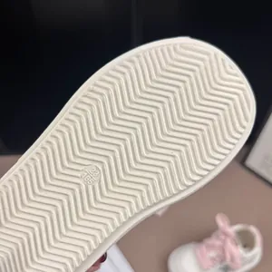 Macro view showing the anti-slip wavy rubber sole texture of children's white casual sneakers
