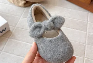 Close-up of grey plush girl's Mary Jane shoe with bow detail and warm fleece lining