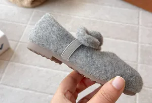 Macro view of soft gray fuzzy winter girl's Mary Jane shoe showing plush material
