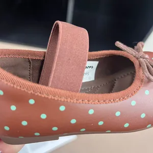 Detailed close-up of brown polka dot girls' Mary Jane flats with elastic strap design