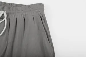 Close-up of grey corduroy pants featuring white drawstring waist and side pocket detail