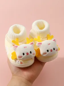 Close-up of yellow fleece-lined baby shoes with 3D plush cat and heart antlers