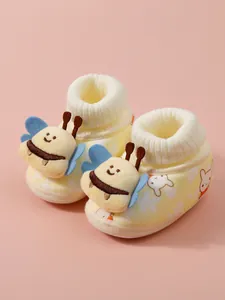 Close-up detail of plush baby booties featuring a cute 3D bee decoration and warm fleece