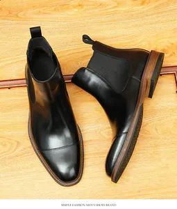 Elegante schwarze Chelsea-Boots aus Leder für Herren mit klassischer Zehenkappe auf Holz.