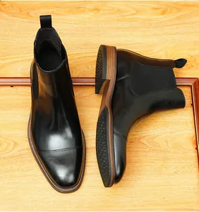 Detailansicht schwarzer Chelsea-Boots aus Leder für Herren auf einem Holzuntergrund