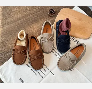 Detailed view of kids' suede loafers featuring a bow design in brown, khaki and navy