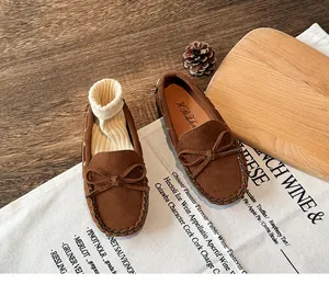 Close-up detail of brown suede children's loafers with bow and hand-stitched accents
