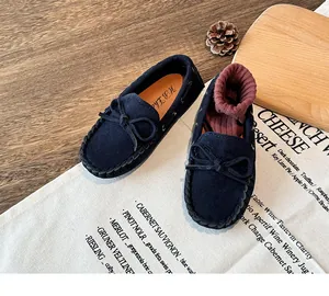 Close-up of navy blue suede children's moccasins with decorative bow and stitched detail