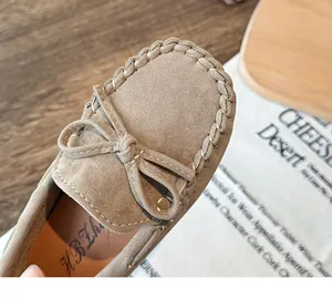 Close-up of children's khaki suede loafers showing bow detail and stitching.