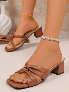 Close-up detail of brown cross-strap block heel sandals with elegant braided design
