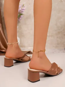 Detailed view of stylish brown cross-strap mid-heel chunky sandals on a model