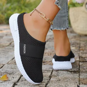 Detailansicht der atmungsaktiven schwarzen Fly-Knit-Mesh-Pantolette für Damen am Fuß im Freien
