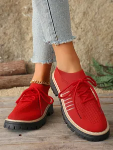 Close-up of red breathable knit sneakers with thick soles and lace-up design for women