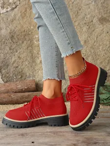 Close-up of vibrant red knit platform sneakers with lace-up detail and thick lug soles