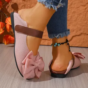 Detalle de elegantes zapatos planos rosas con un lazo grande y correa marrón