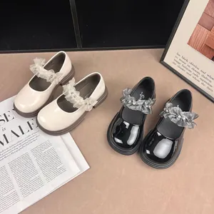 Detail showing black and beige girls' Mary Jane shoes with ruffled lace and pearls