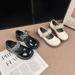 Close-up of girls' glossy Mary Jane shoes featuring delicate lace and pearl trim