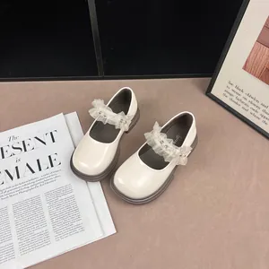Detail of elegant cream girls Mary Jane shoes featuring lace ruffles and pearl accents