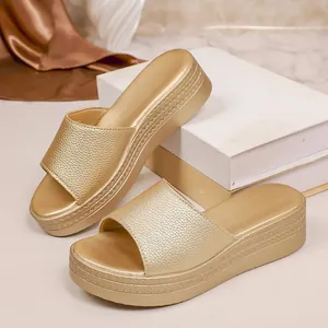 Detail shot of golden platform wedge slippers showing the metallic texture and braided sole edge.