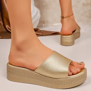 Detail of gold platform wedge sandals with metallic textured strap on foot.
