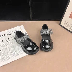 Detailed view of girls' black patent leather shoes with ruffled pearl straps
