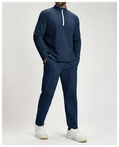 Model wearing a dark blue men's quarter-zip athletic set with matching trousers and sneakers.