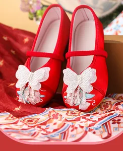 Detail view of traditional red embroidered shoes for girls with butterfly and pearl tassels