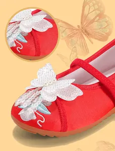 Detailed close-up of girls' Hanfu shoes with red embroidery and butterfly pearl ornament