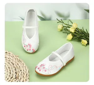 Detailed macro shot of white traditional embroidered girls' cloth shoes with pink flowers.
