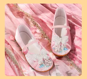 Exquisite detail view of pink girls Hanfu embroidered shoes with butterfly and pearl accents.