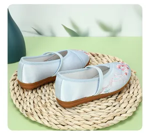 Detail of light blue traditional Chinese embroidered shoes for girls with floral patterns.