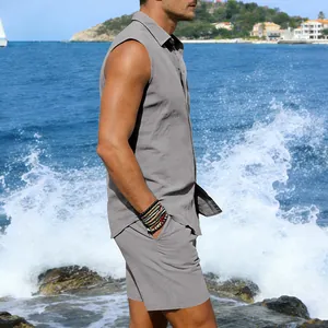 Side view of a man wearing a grey linen sleeveless shirt and shorts set on a rocky beach