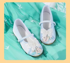 Detail of light blue girls' Hanfu embroidered shoes with pearly butterfly decoration.