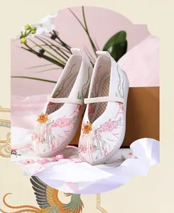 Close-up detail of traditional Chinese child's Hanfu shoes with pink floral embroidery.