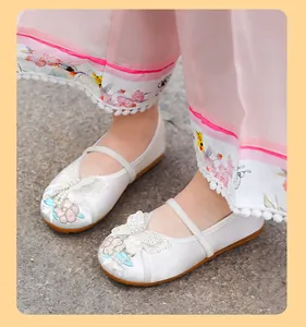 Close-up of white traditional Chinese embroidery shoes for girls with butterfly decor.