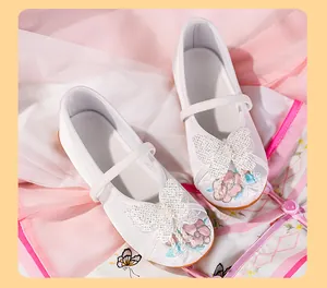Close-up of white children's Hanfu embroidered shoes with glittery butterfly and flowers.