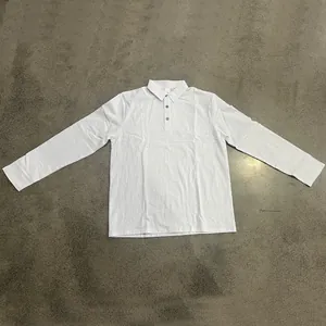 Detail view of a white linen long-sleeve polo shirt laid flat on a textured floor